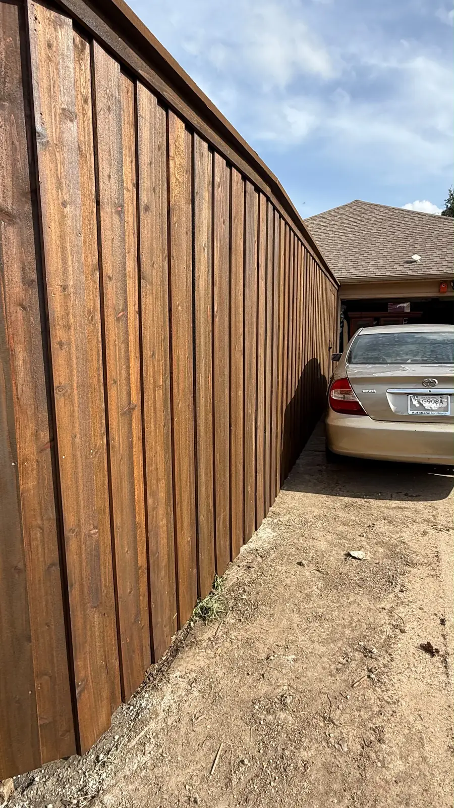 Dark-stained board-on-board standing tall over the driveway