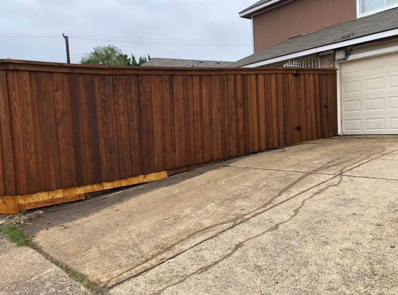 Stained cap-rail fence at a driveway gate