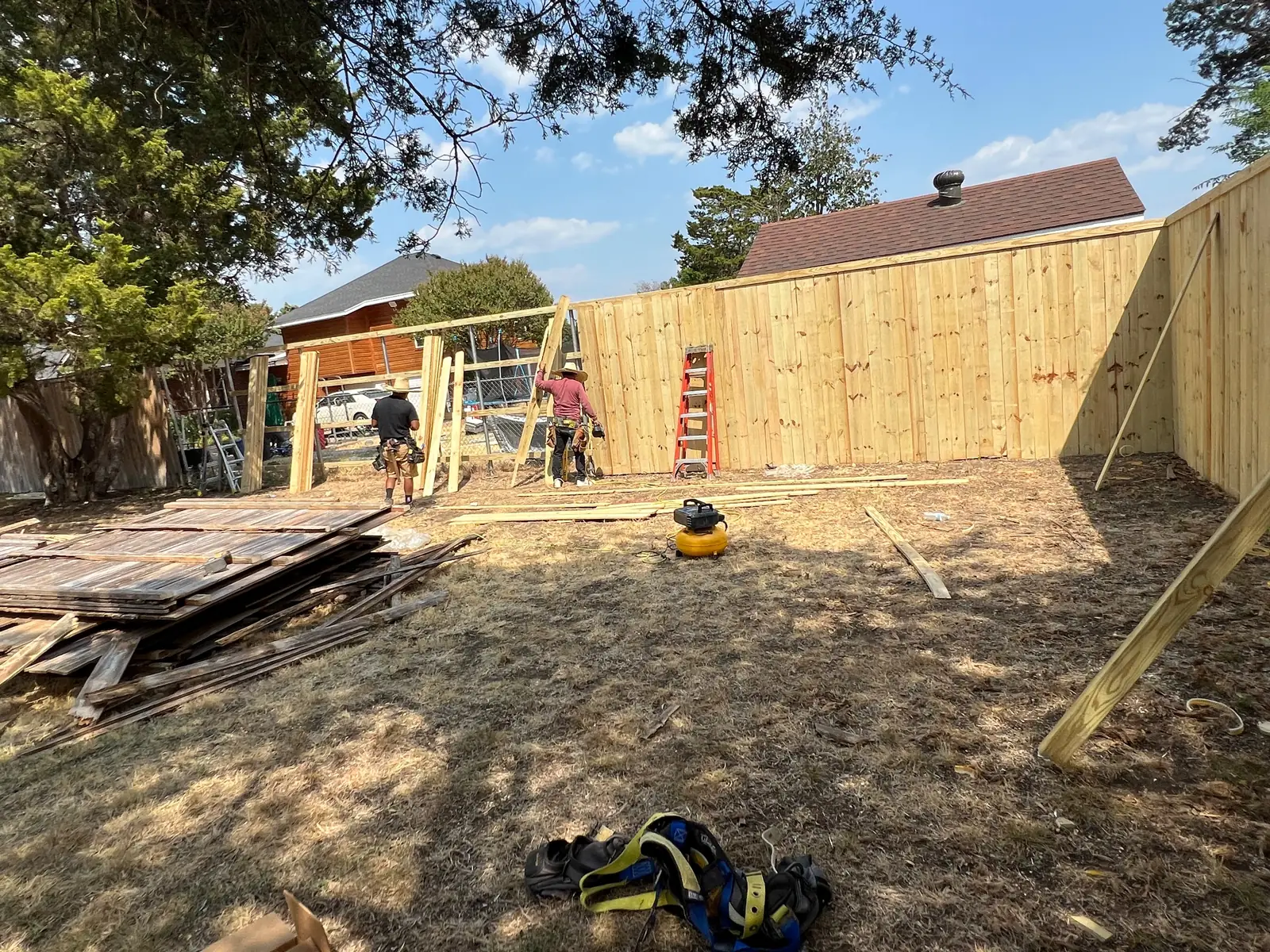 Crew removing old fence panels beside the new pine fence