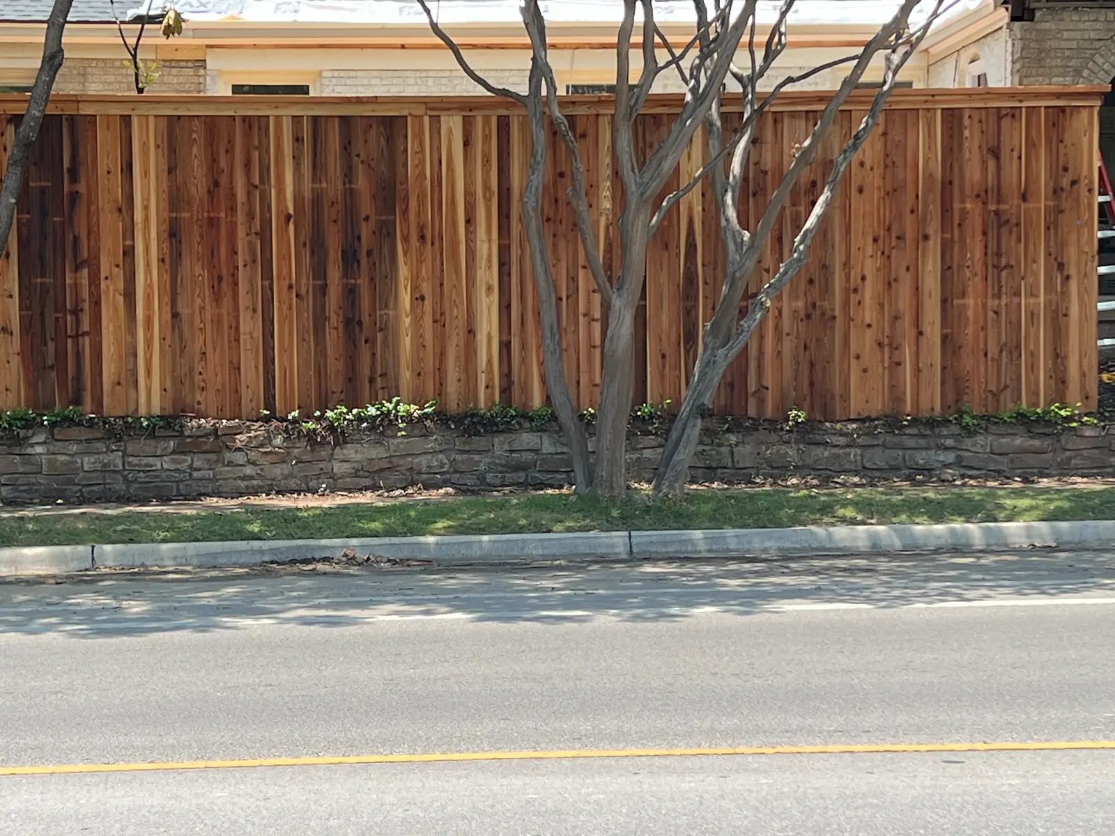 Cedar board-on-board with cap rail over a stone retaining wall